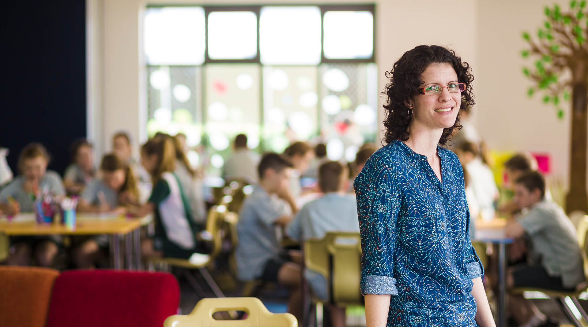 Teacher smiling at camera in front of children