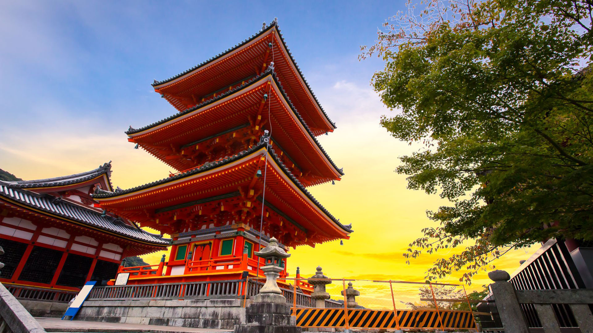 A red temple in Japan with green tree beside it.