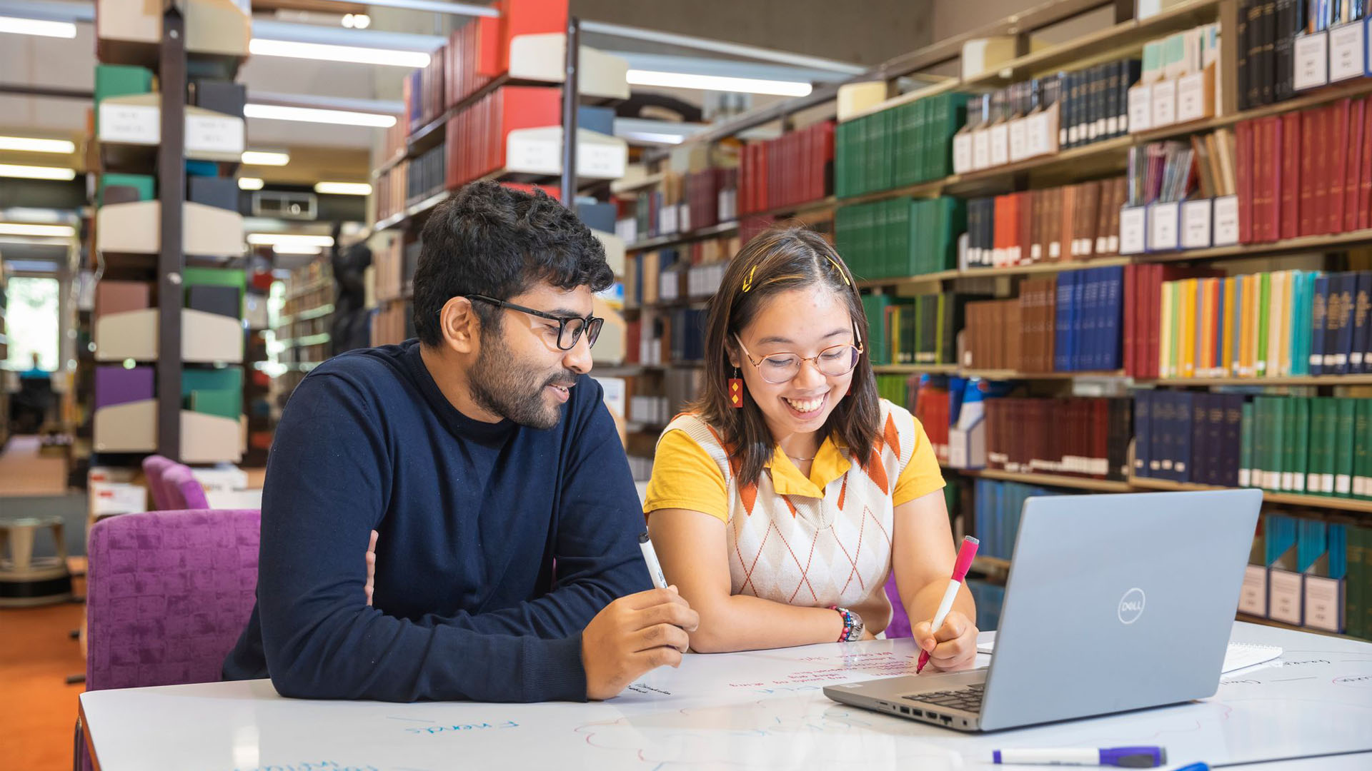 A male student and a female student sit together to study, while smiling. 
