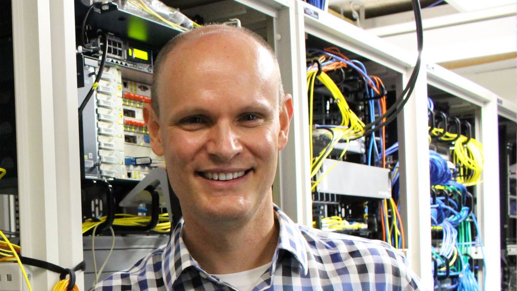A headshot of Bachelor of Biomedical Sciences Associate Professor Matt Field standing in front of a computer server.