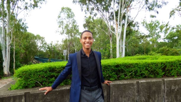 Jonathan Naranjo Galvez leaning against a concrete garden bed and smiling in the direction of the camera. 