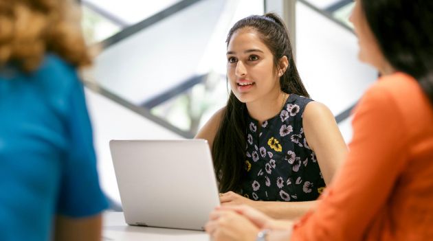 woman using a laptop whilst looking at another woman
