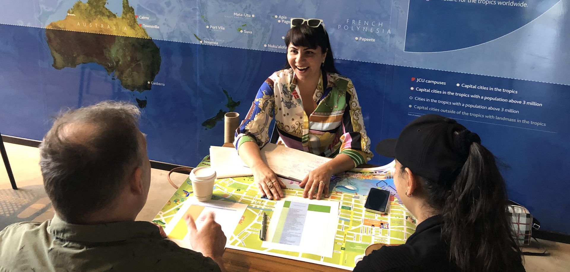 Rana Dadpour at a cafe table interviewing two recent arrivals to Cairns 