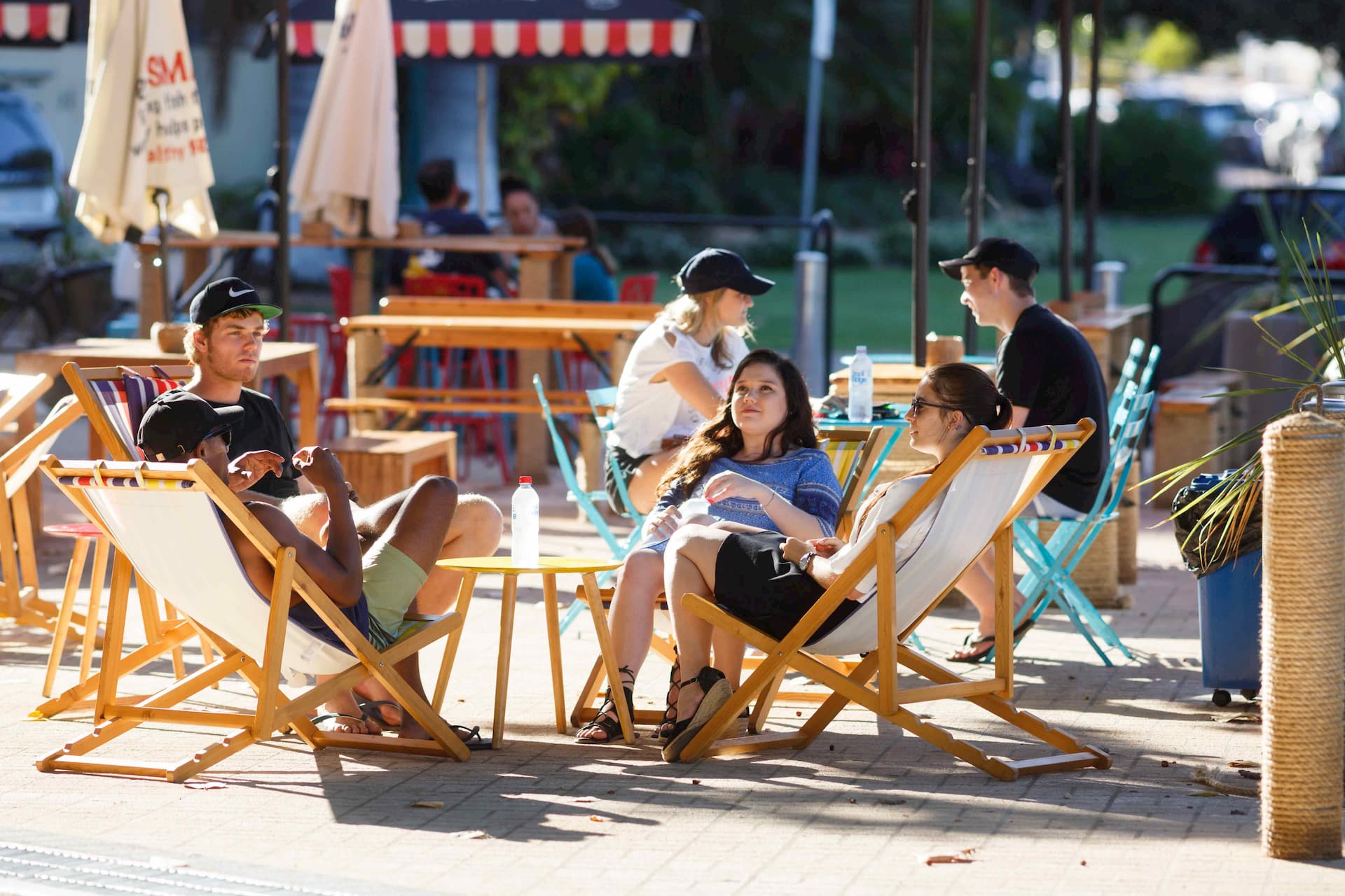 Students sitting around a small table outside, in lounge chairs, relaxing.