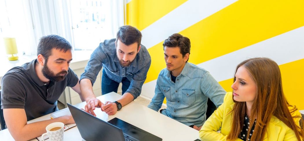 Four people gathering around looking at a computer. 