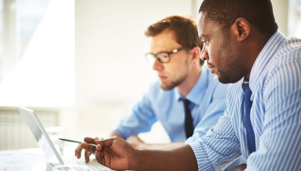 Two men having a discussion about what's on a computer.