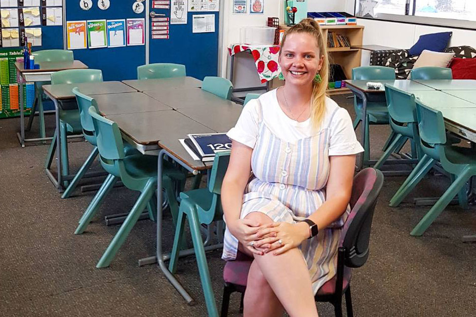 Tia sitting on a chair in a primary school classroom
