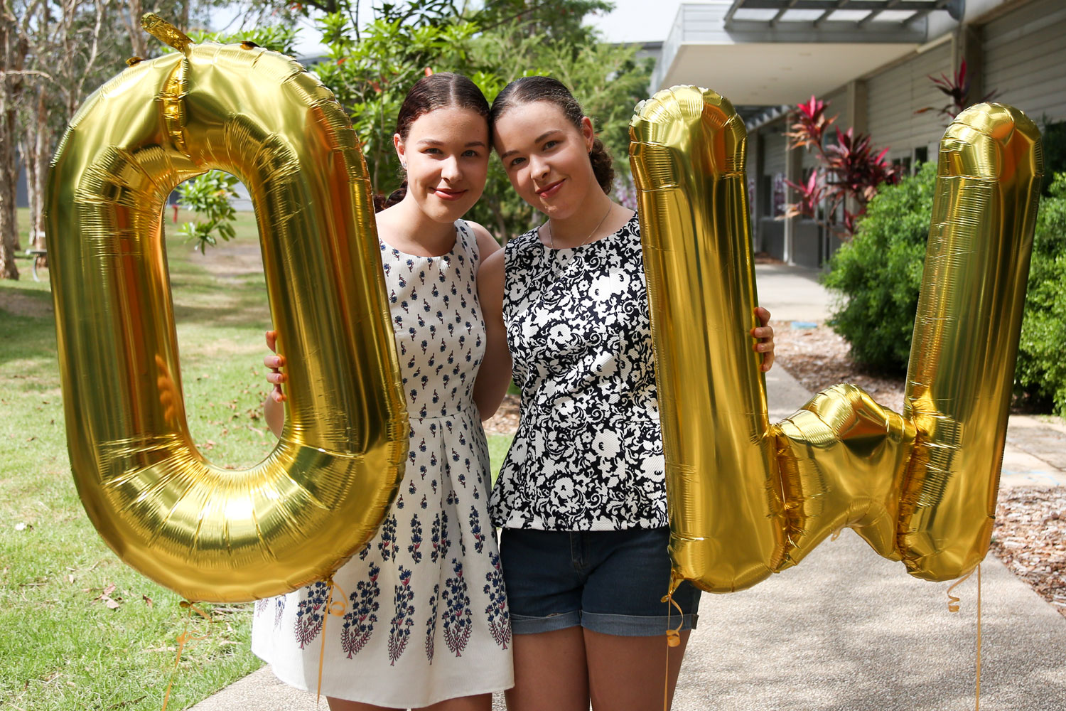 Two female students stand between giant gold 