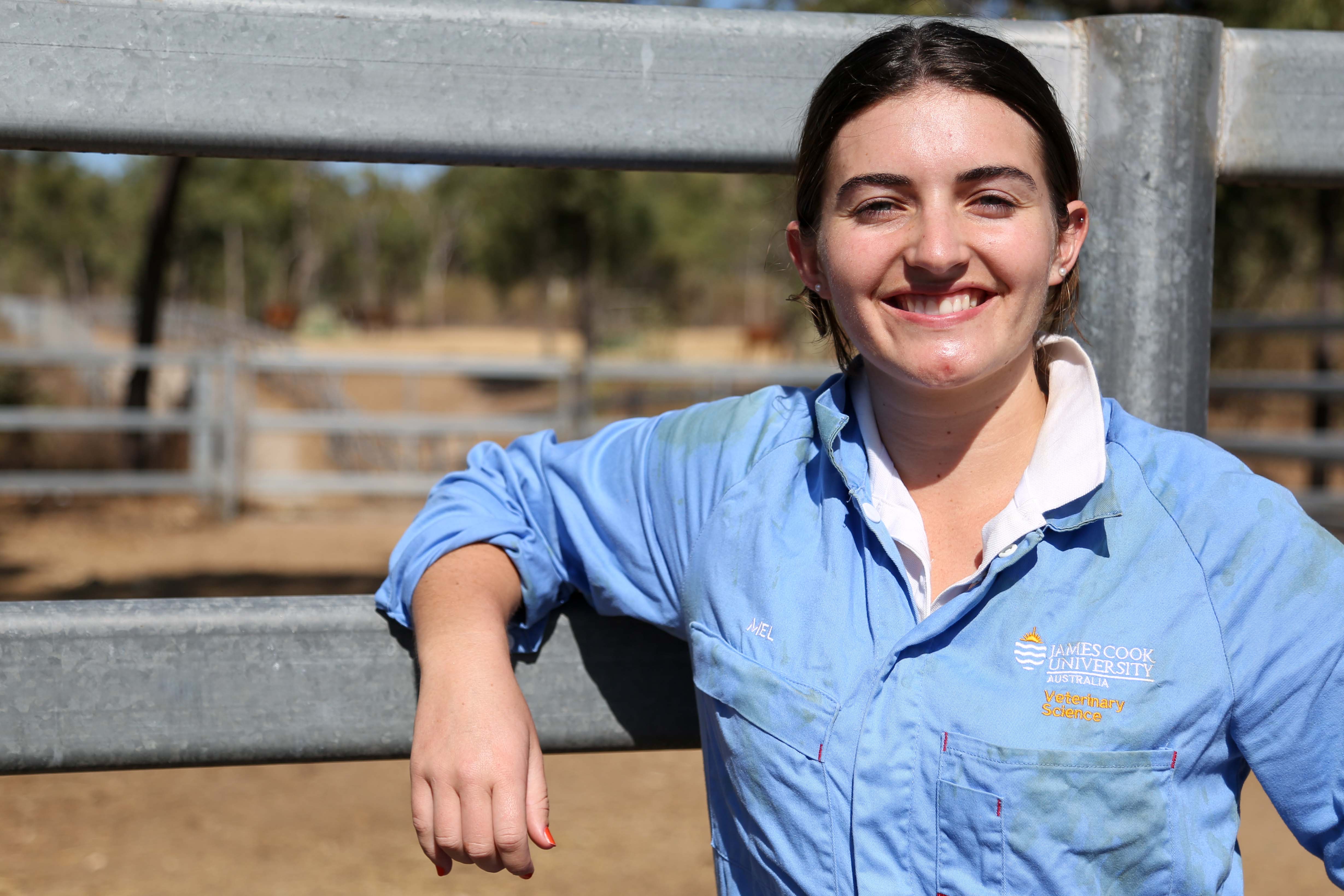 Melanie wears her JCU vet overalls and leads against a fence in the yards