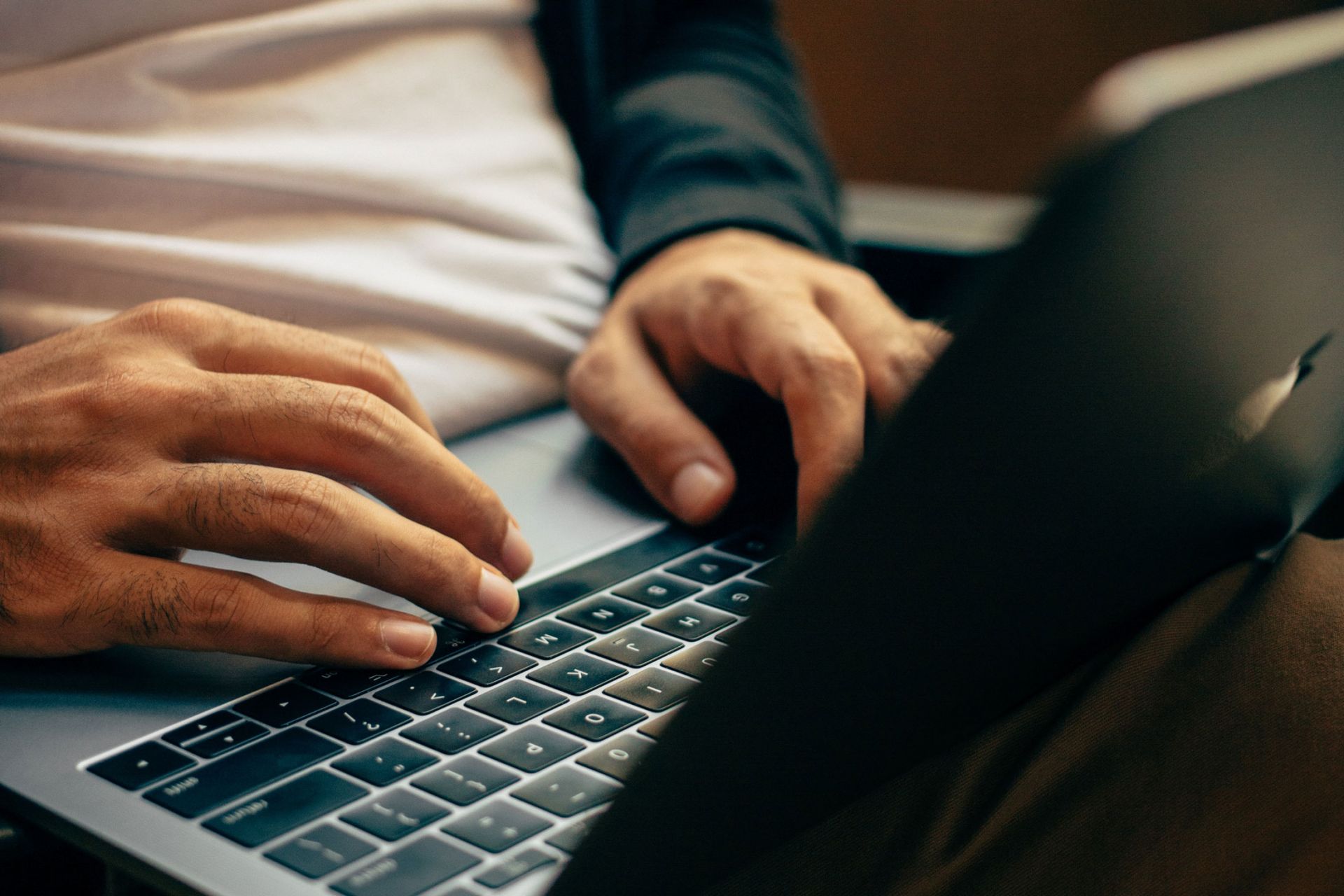 low light, hands in highlight on the keyboard of a laptop, face hidden