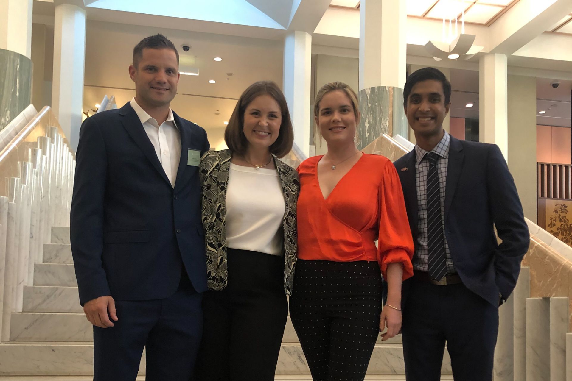 four people pose in a line on the internal steps of Parliament House