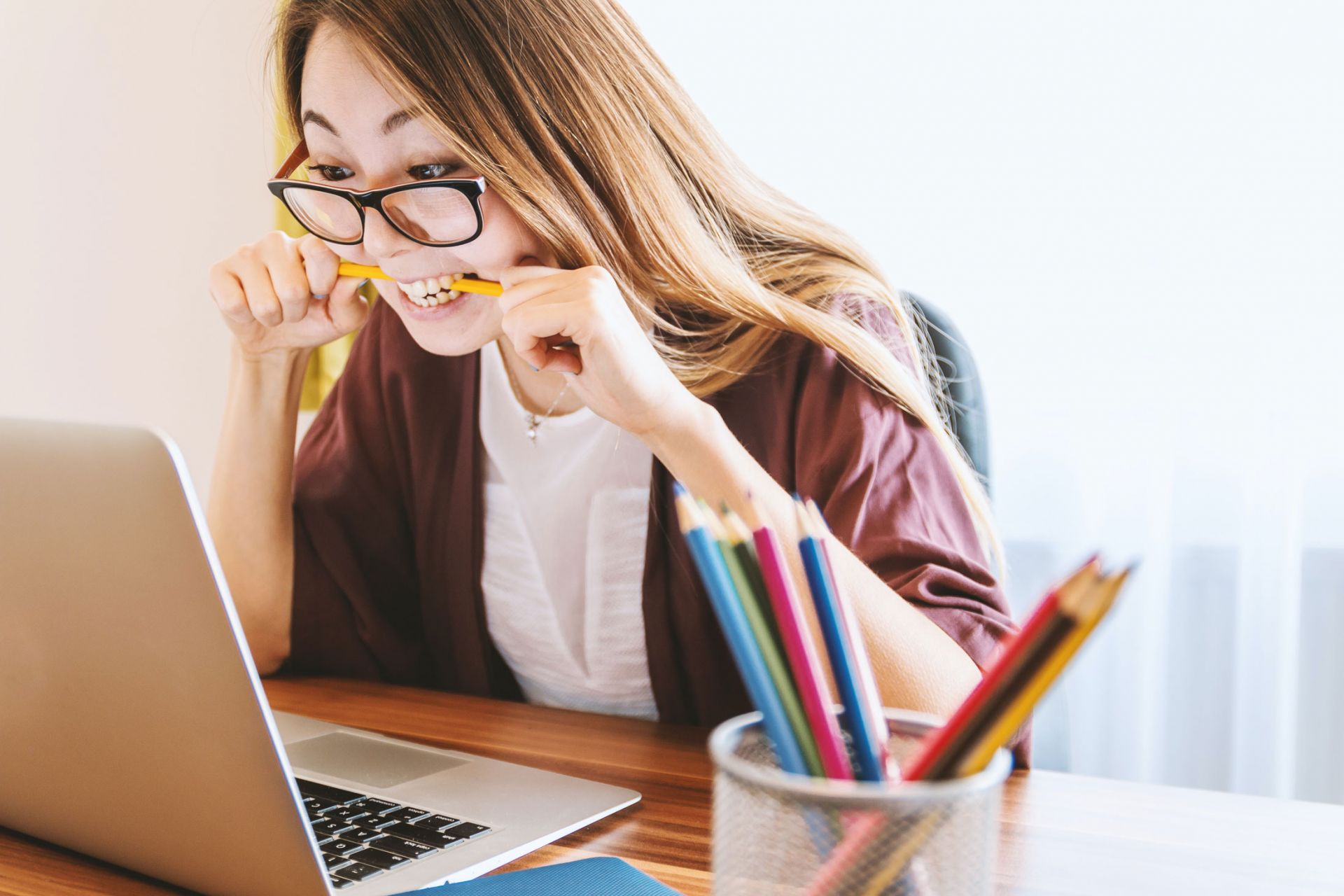 Woman looking at a laptop and biting a pencil