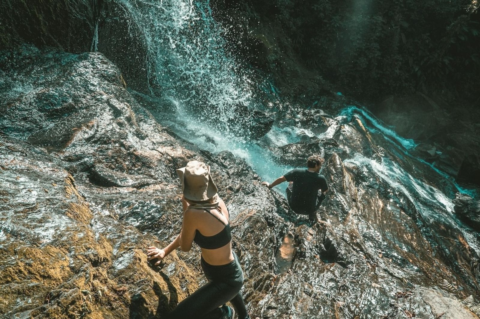 Two people climbing the cliff face of a waterfall.