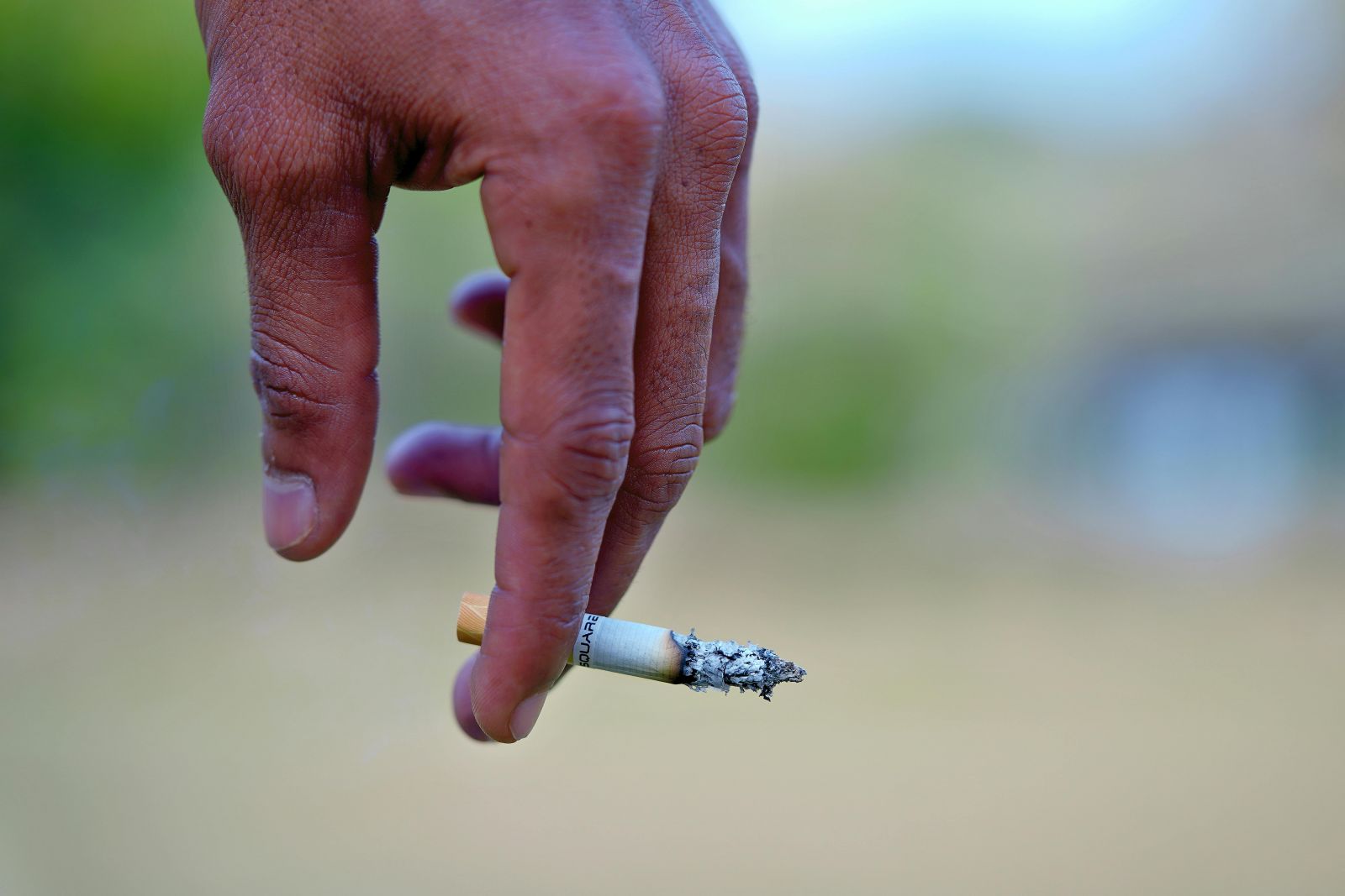 A photo of a hand with a cigarette in it.