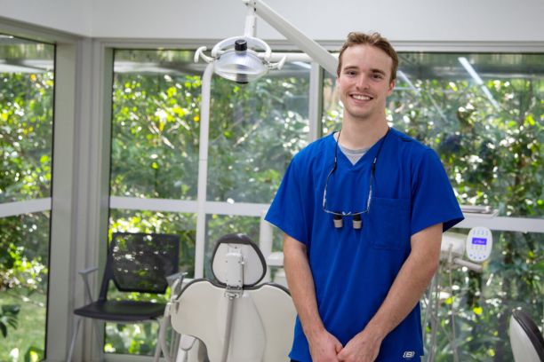 Joel Sutherland in a dental surgery wearing blue scrubs. 