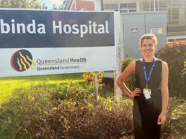 young woman standing at Babinda Hospital sign