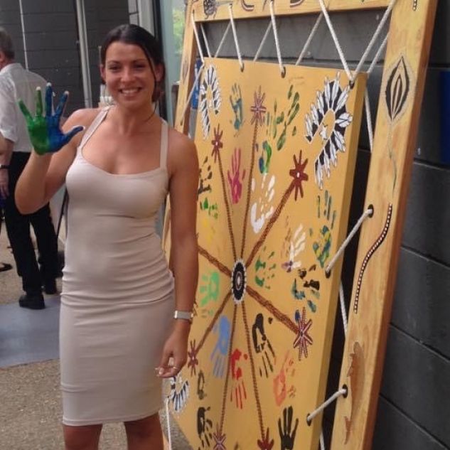 young woman with paint on hand in front of artwork