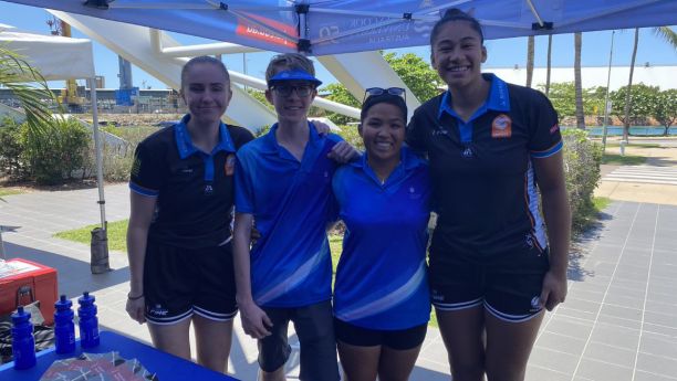 Tia and three other students posing under a JCU marquee at an event. 