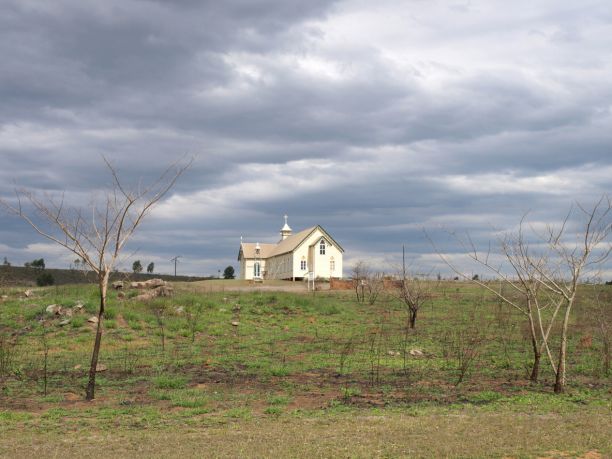 The historic Ravenswood church in the far background with stormy clouds in the sky. 