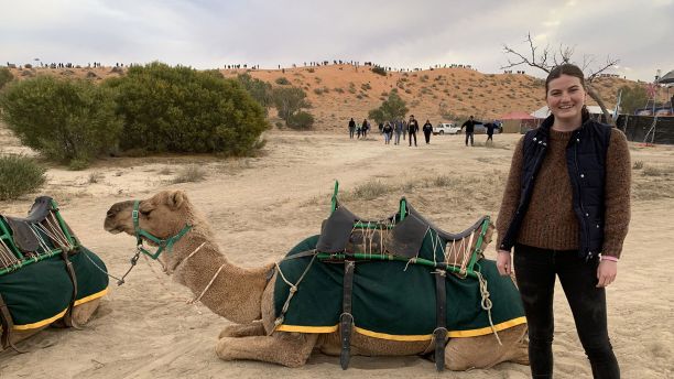 Woman with camel seated on ground