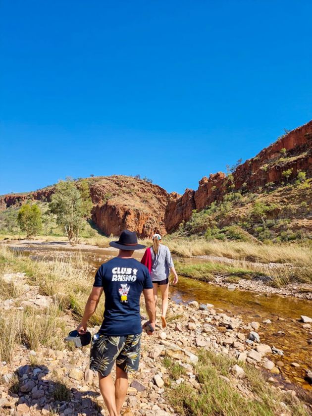 Shot from behind of young man and woman walking through rocks with range in background