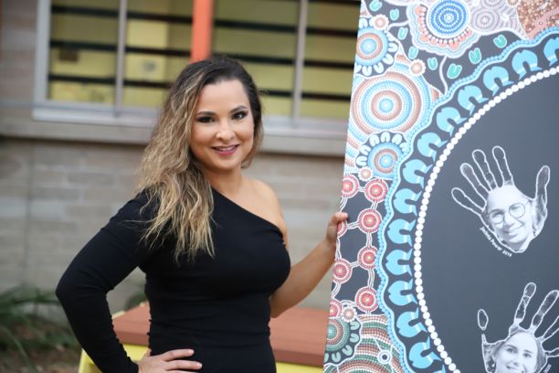 woman next to Indigenous Australian painting
