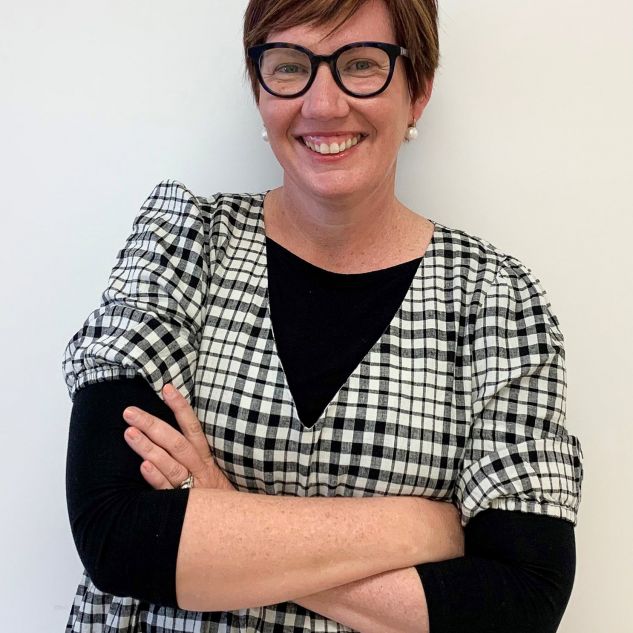 woman in glasses with folded arms and checked dress