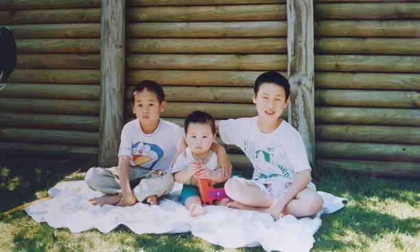 Three young boys on blanket in yard