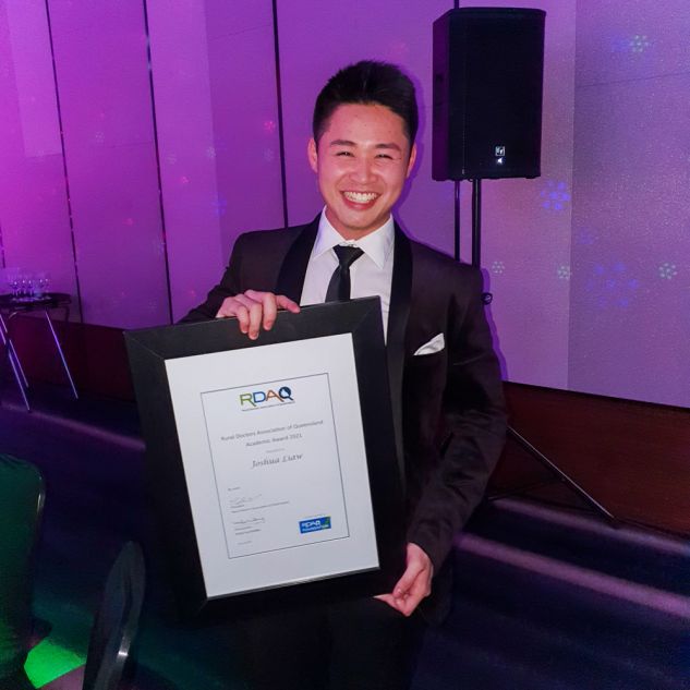 Young man holding framed award certificate for RDAQ Academic Award
