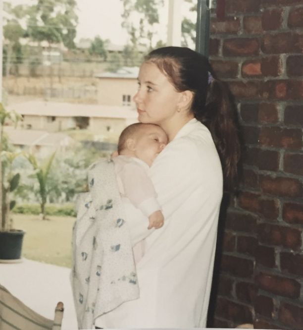 JCU Alumni Melissa Redsell when she was a teenager holding her baby in her arms swaddled in a blanket. 