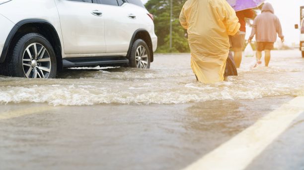People and cars struggle through flooded street
