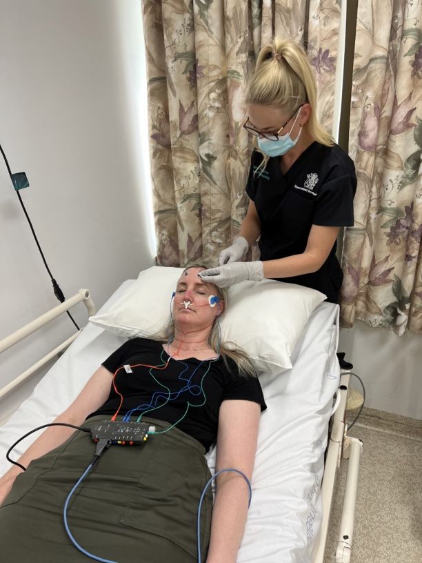 Laura helps a patient put on monitoring equipment. 