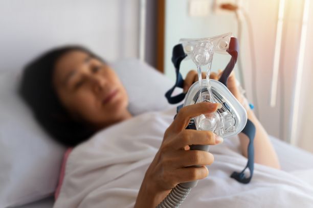 A woman holds a sleep apnea mask. 