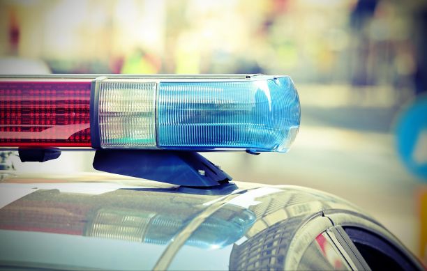 Top of a police car with only the roof of the car and the blue and red lights visible during the day