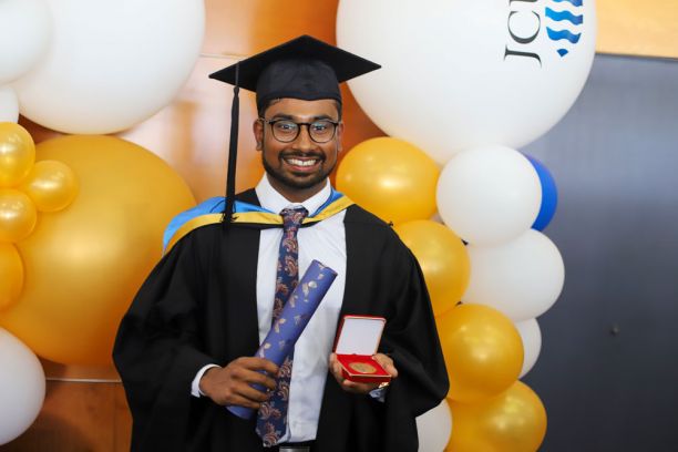 Medical graduate in cap and gown with medal and certificate