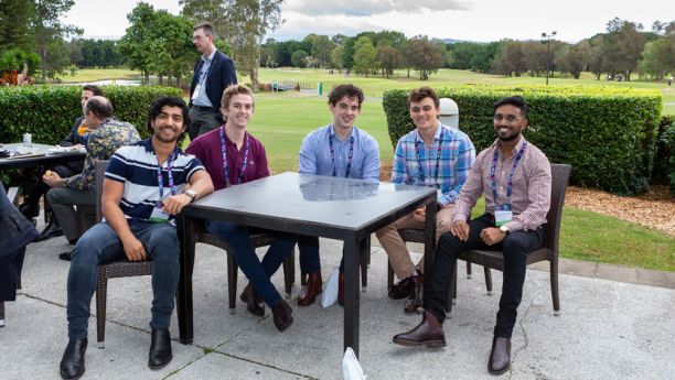 five men sitting at table outdoors
