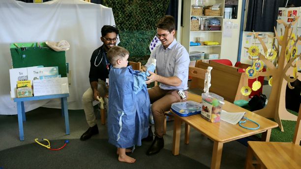 two medical students with young student dressed in PPE